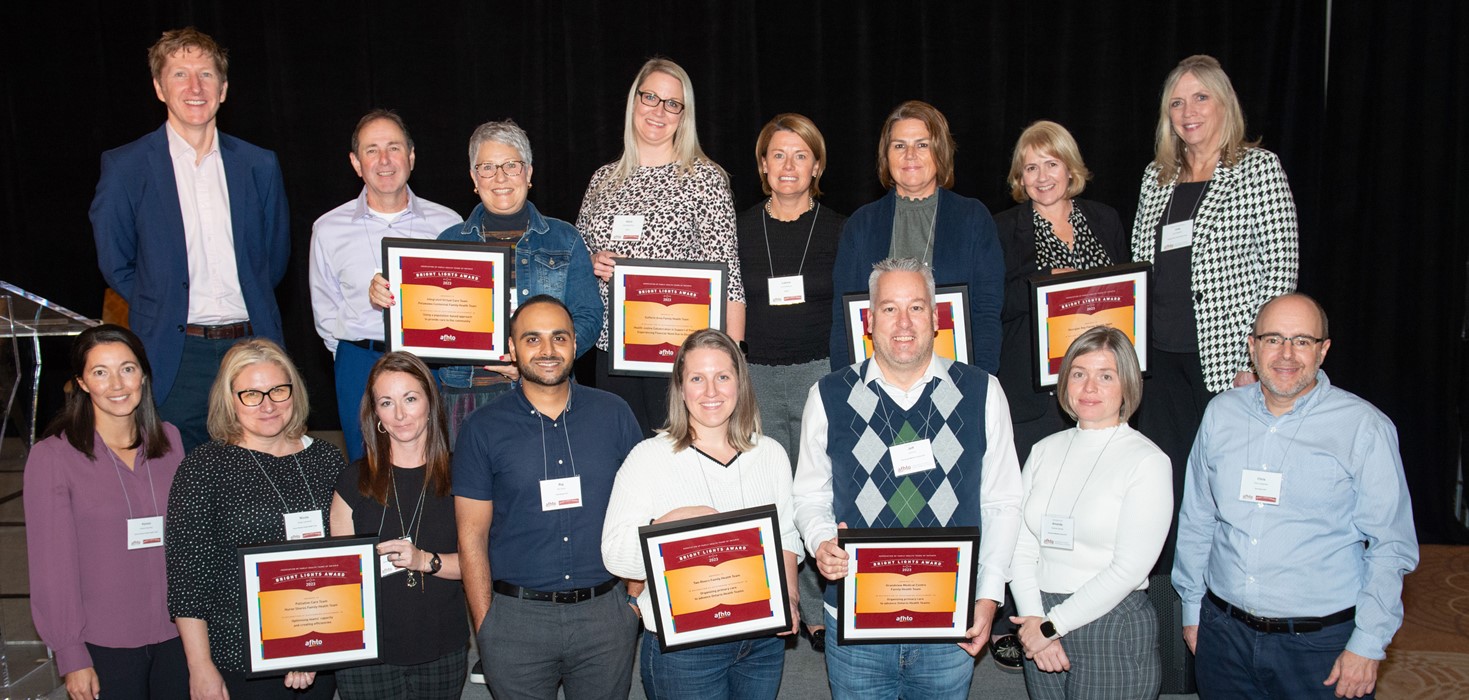 A group of people with award plaques and lanyards smile