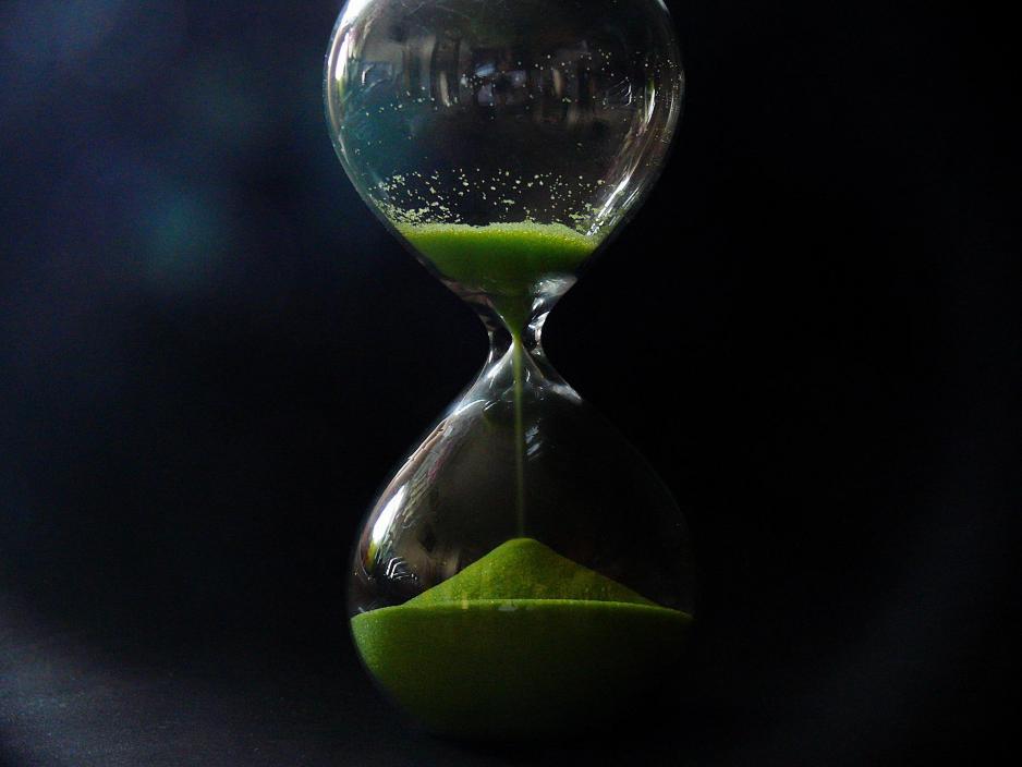 Hourglass with green sand sits in shadow
