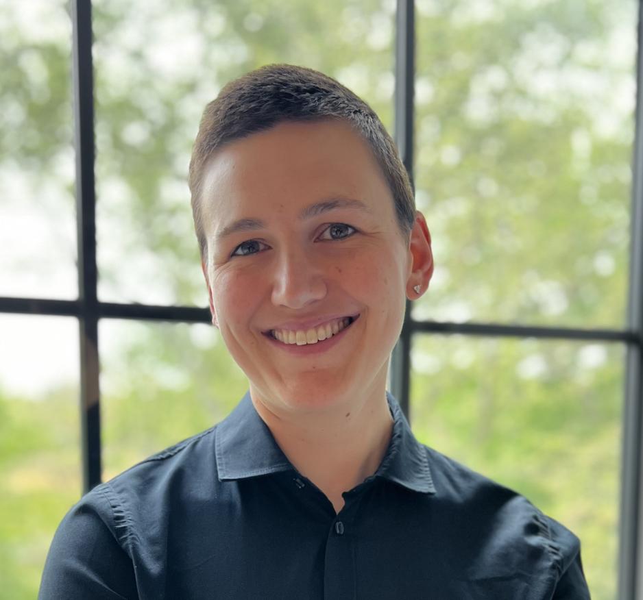 Dr. Jaky Kueper in a dark button down shirt, smiling in front of a window